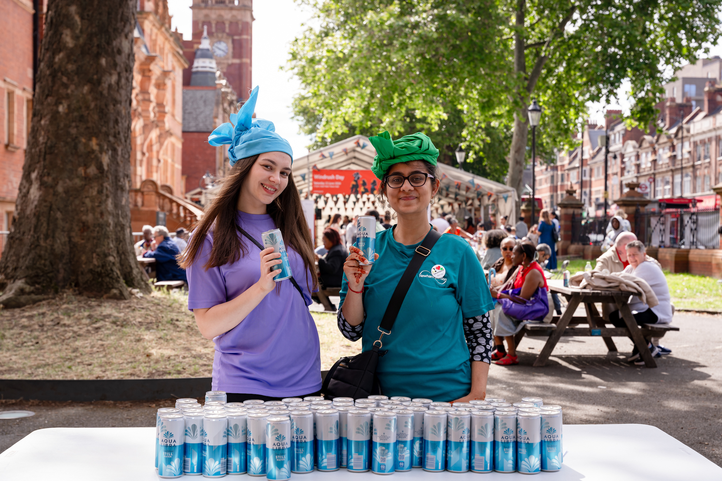 2 ladies volunteering and holding cans of water