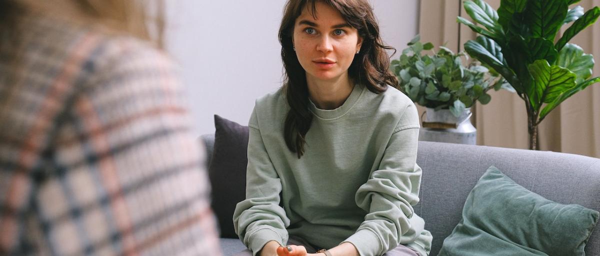 woman sitting on a sofa talking to a support worker