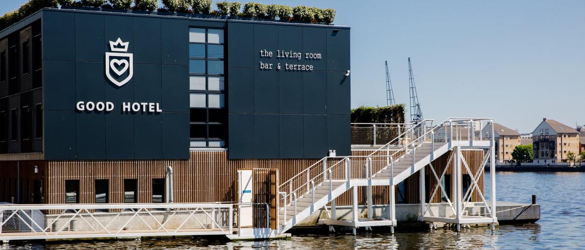 The Good Hotel is a large black building overlooking the water.