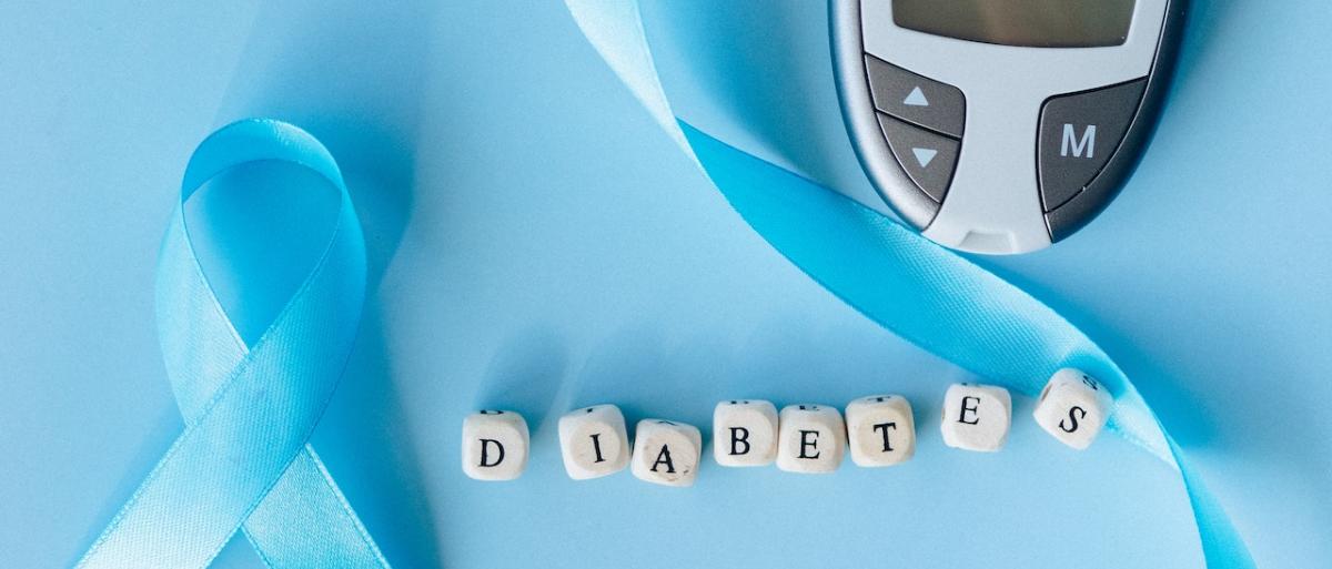 World Diabetes Day image with a blue ribbon, blood sugar monitor and scrabble letters spelling diabetes