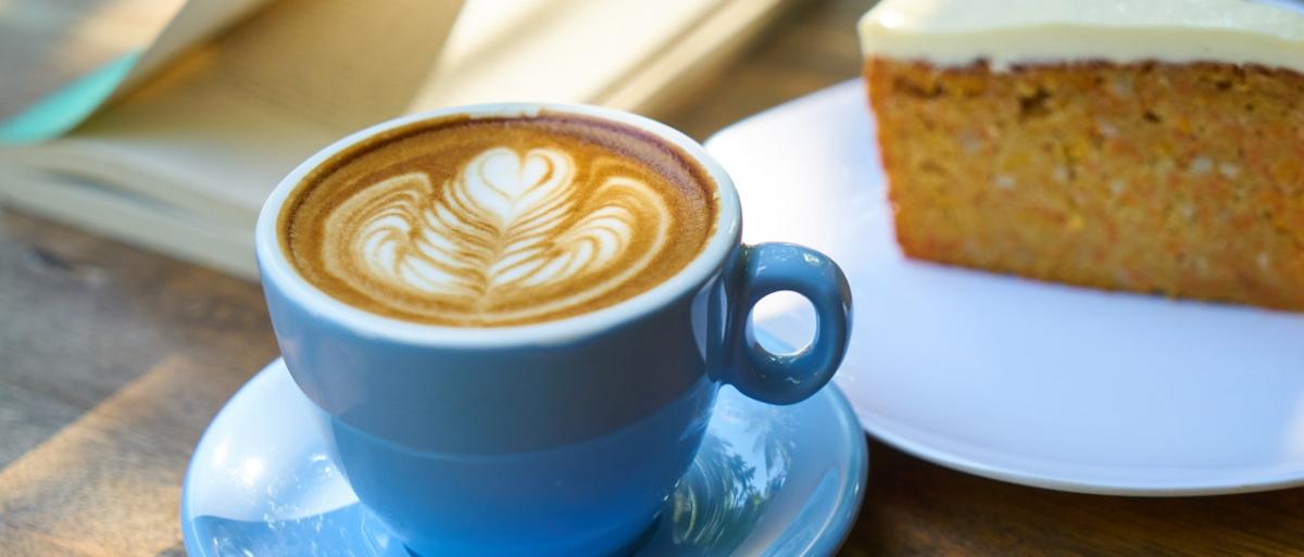 Cup of coffee on a wooden table with a slice of carrot cake