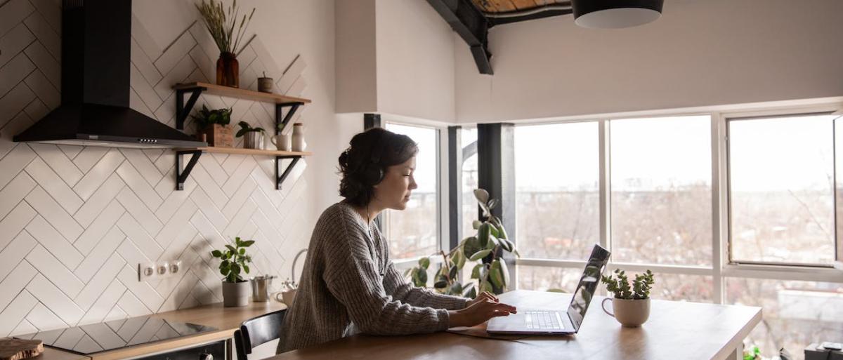 Lady sitting in her kitchen on her laptop