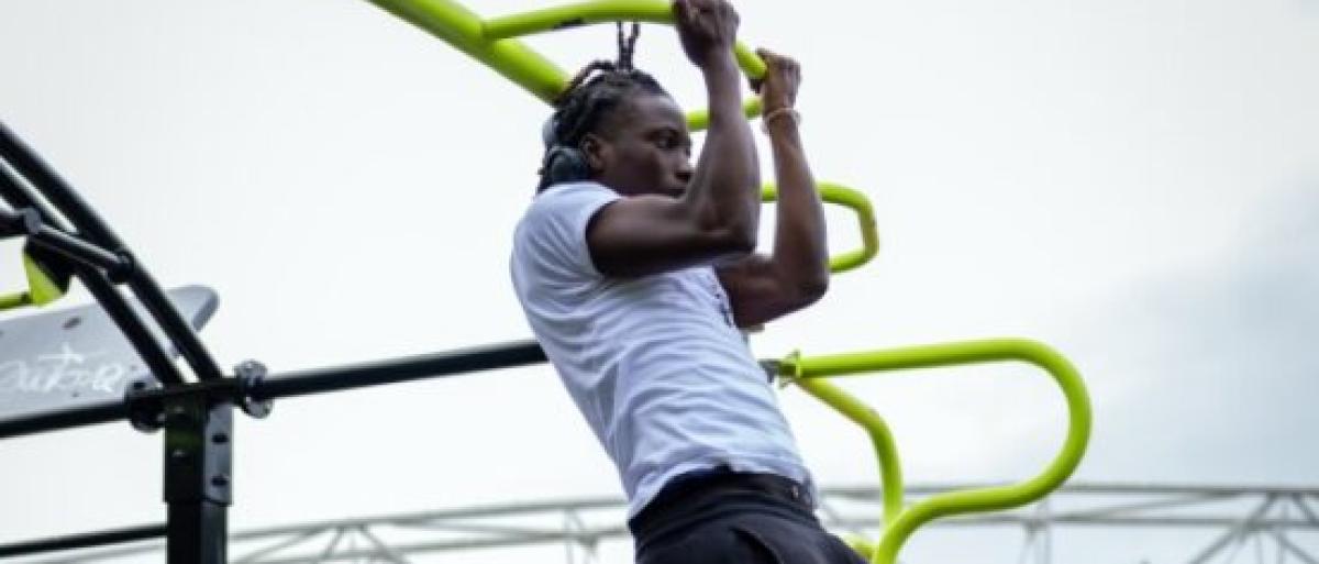 Young man doing pull ups on gym equipment in a park