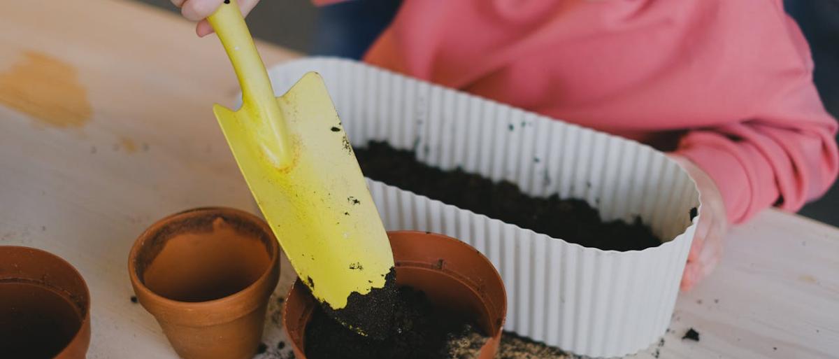 A child putting soil in a flower plant