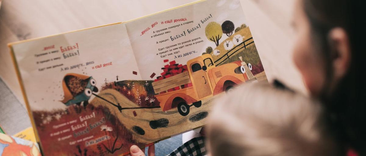 A parent holding and reading a book to a child