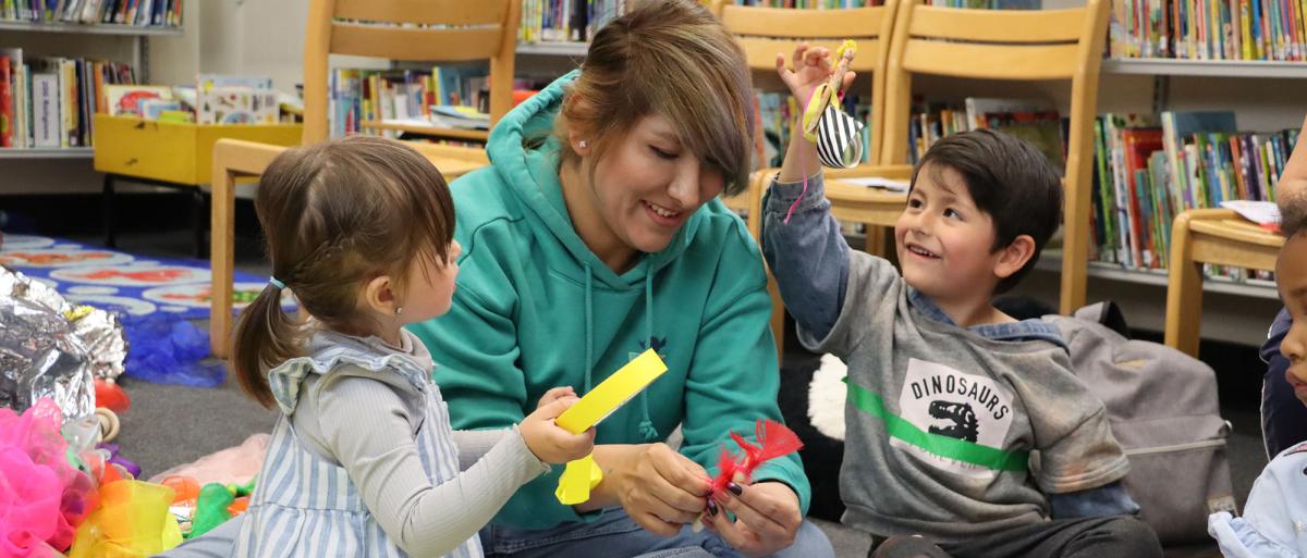 2 children holding arts and crafts items with an adult