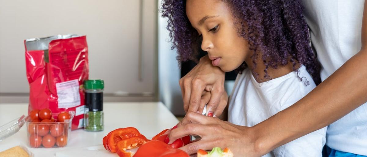 A child and adult cutting tomatoes