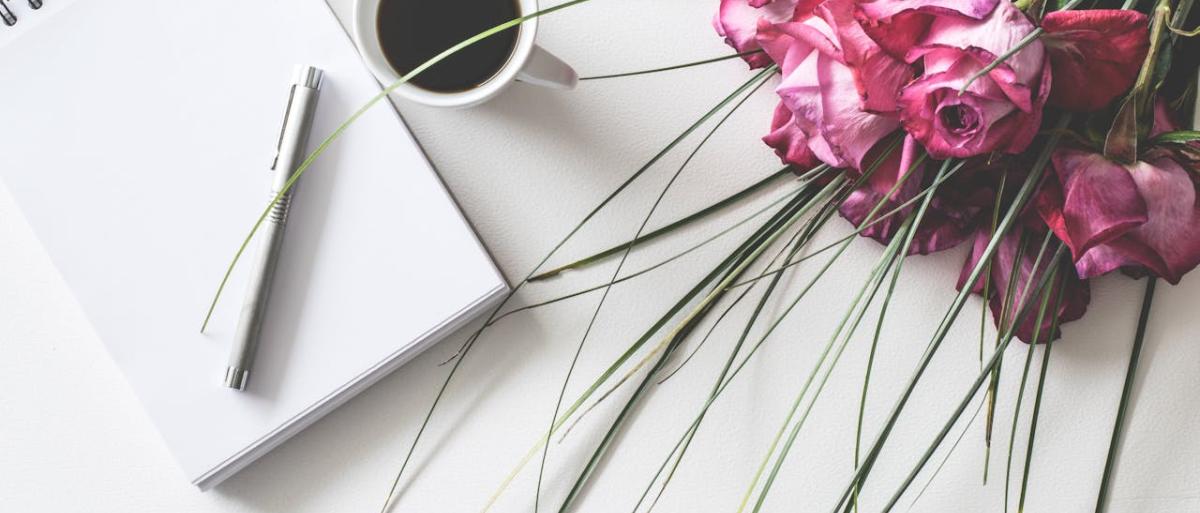 Notebook with pen, cup of coffee and flower