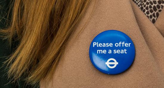 Please offer em a seat badge on a lady's brown coat