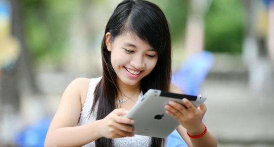 Teenager using an iPad and smiling