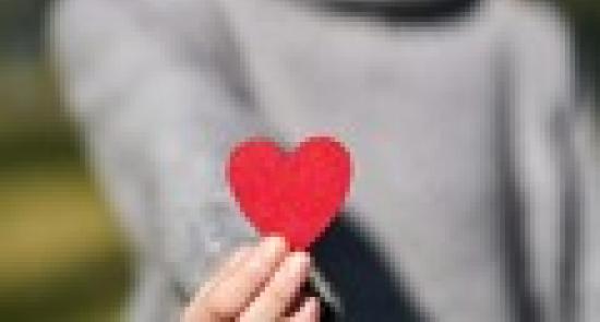 Woman holding out a red paper heart